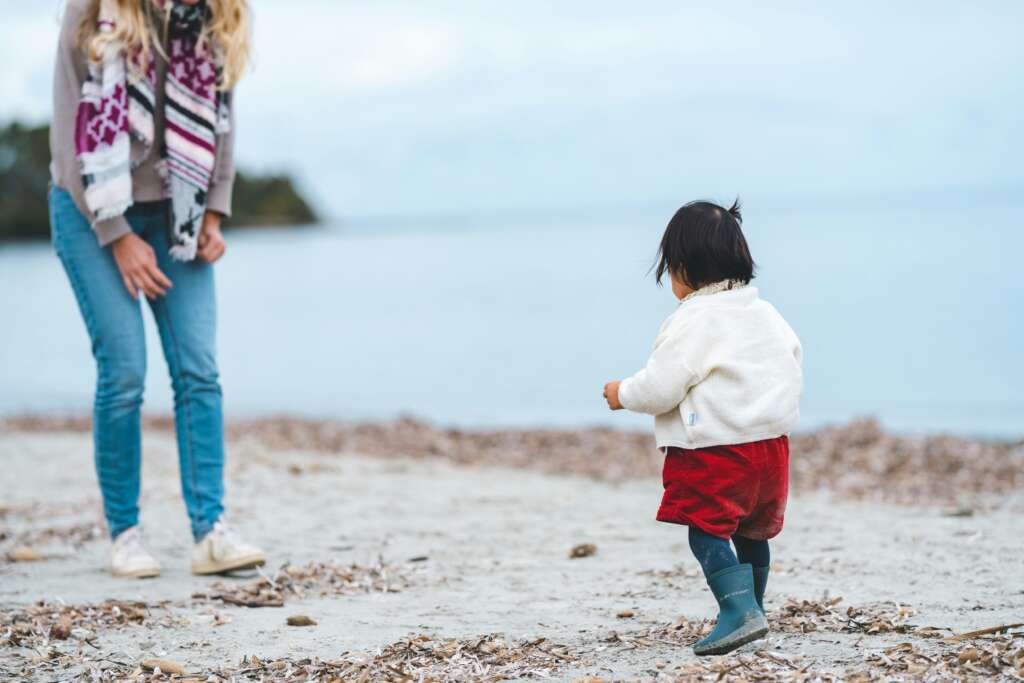 Una mamá viendo a su pequeña hija caminar.